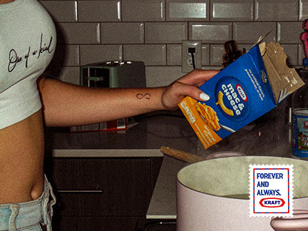 photo of a wrist with an infinity sign on it pouring mac and cheese into a pot